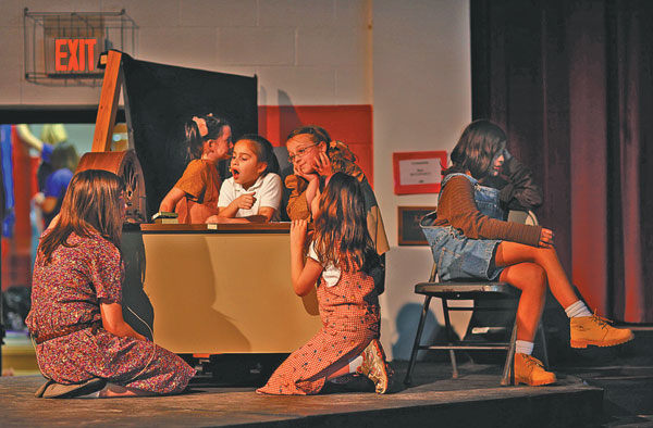 Above, the principal orphans from the production Annie, Jr. listen as Annie sings on the radio. Kneeling in front are Rebecca Osborn and Marjorie Mitalski, both from St. Aloysius School. Seated at the desk (l-r) are Erin Klasing, Little Flower; Esmeralda Silva, Little Flower; and Grace Trello, St. Aloysius. Seated in the chair is Alexa Huerta, Little Flower.